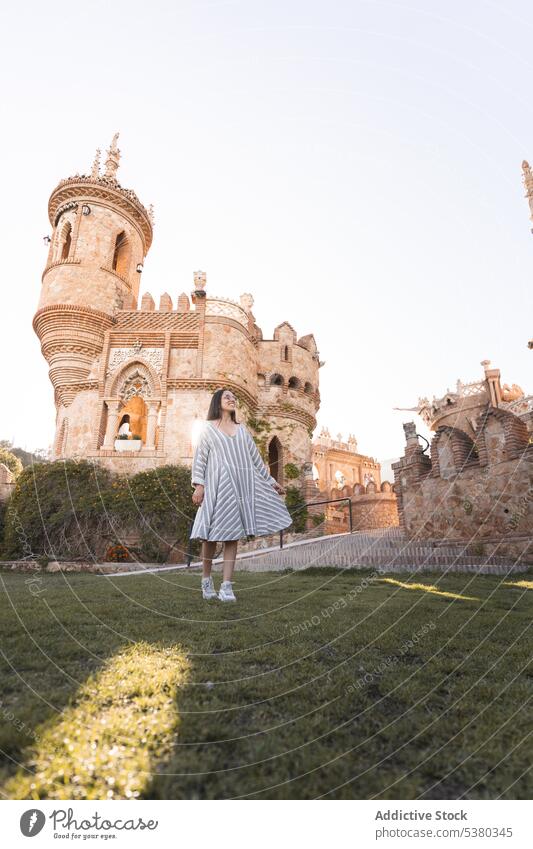 Young woman walking in park near castle tourist admire architecture vacation sightseeing smile lawn historic young female daytime blue sky journey tourism