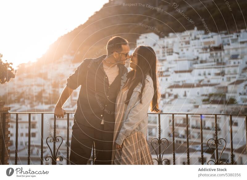 Loving couple standing close on balcony smile hug sunset mountain city evening relationship summer young happy love embrace romantic cheerful sundown sunglasses