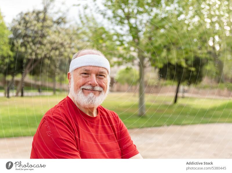 Happy elderly man smiling at camera in park happy athlete fitness sport positive smile wellbeing portrait healthy lifestyle confident male senior beard