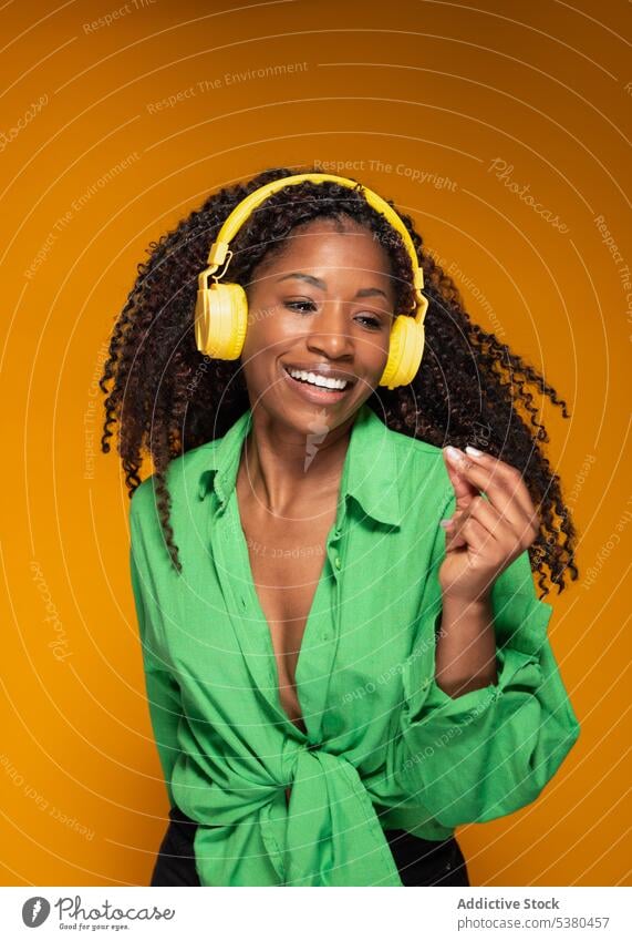 Woman in earphones listening to melody and dancing woman headphones dance music smile happy orange female black african american meloman headset song playlist