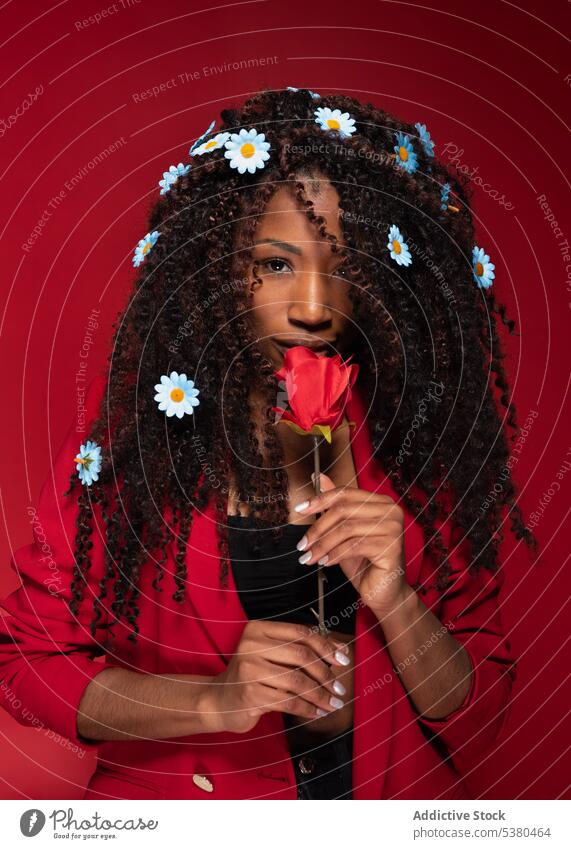 Sensual woman with flowers in curly hair holding rose romantic jacket fresh floral portrait red style elegant bloom female young bright african american tender