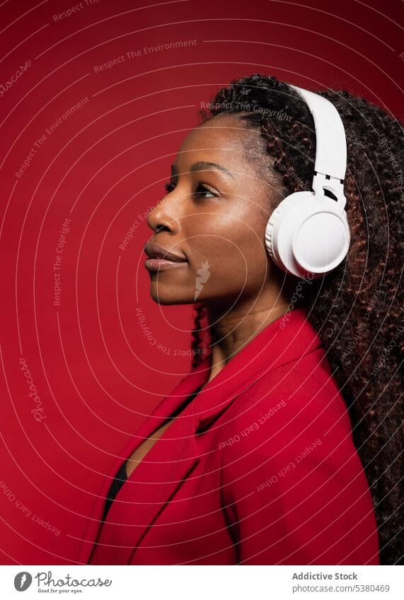 Thoughtful woman listening to music with headphones serious wireless style trendy melody positive black female african american song device modern meloman sound