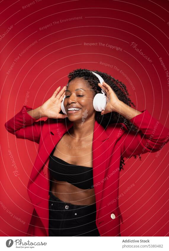 Cheerful woman with hands on headphones listen music wireless style smile trendy happy melody positive black female african american song device modern meloman