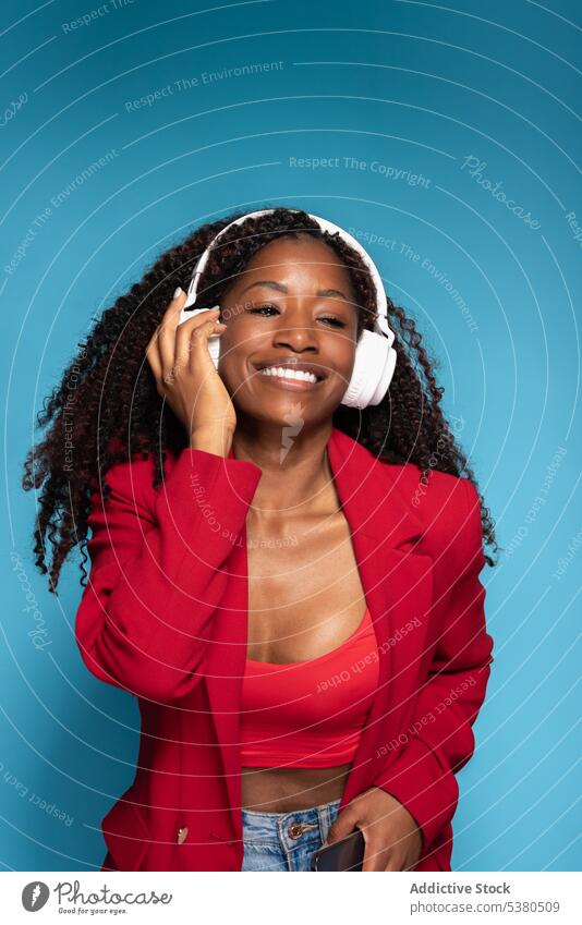 Cheerful woman in headphones listening to music studio wireless song style positive audio female african american happy enjoy confident smile optimist gadget