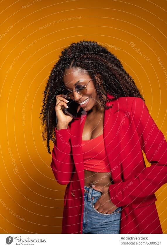 Cheerful lady speaking on smartphone in studio cheerful woman conversation smile phone call style trendy outfit positive talk female african american happy