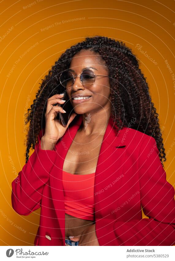 Happy lady speaking on smartphone in studio woman conversation smile phone call style trendy outfit positive talk female african american happy black young