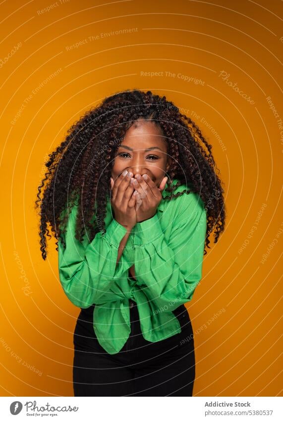 Excited woman in green shirt laughing model smile excited thrilled curly hair dark hair style portrait female black african american joke humor joy euphoria