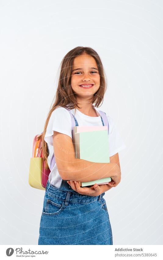 Cheerful schoolgirl with backpack smile positive student kid education happy notebook pupil child denim carry little glad studio shot knowledge childhood