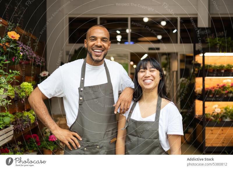Happy multiethnic coworkers in aprons in floristry shop woman smile together cheerful couple store colleague staff young job multiracial happy positive