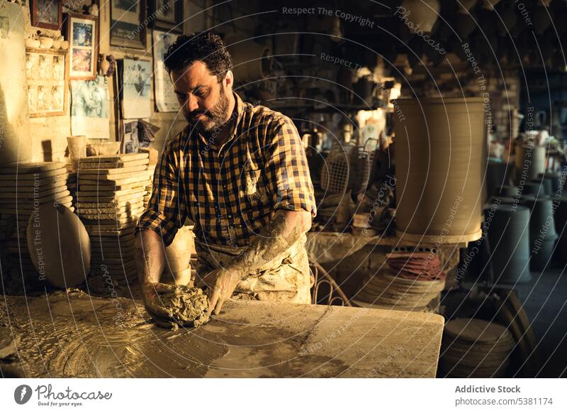 Focused craftsman creating clay pot at workbench in pottery workshop artisan concentrate mold create master tradition male middle age ethnic brunet skill