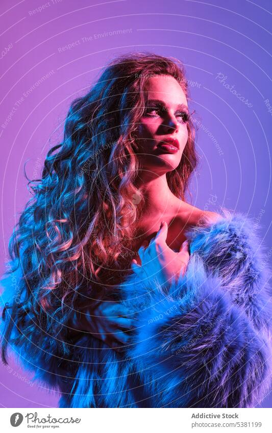 Stylish young woman wearing blue fur jacket model 80s fashion festive retro charm makeup neon female fair hair hairstyle individuality appearance vibrant