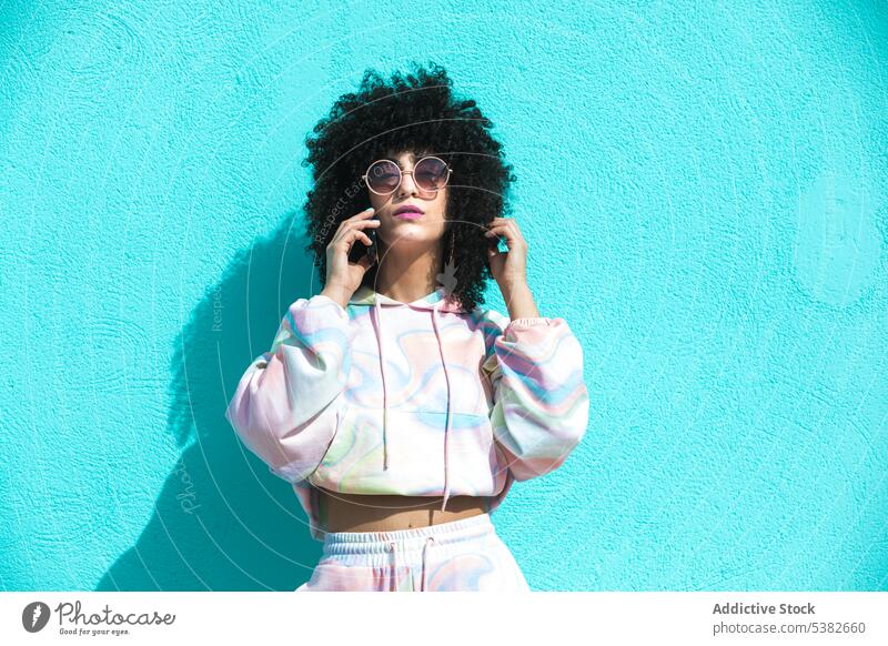 Stylish ethnic woman in sunglasses talking on smartphone phone call speak conversation serious young female hispanic mobile style cellphone gadget device afro