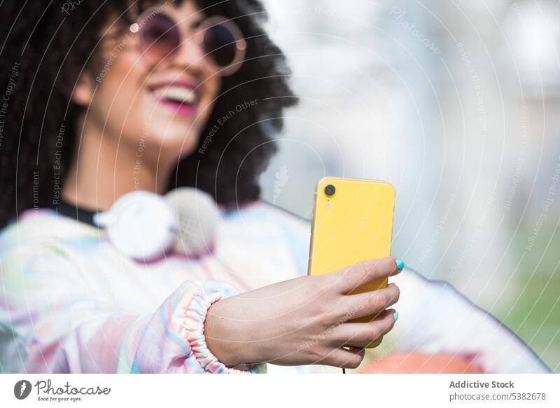 Cheerful ethnic woman taking selfie with smartphone happy cheerful sports ground fence self portrait moment summertime young female hispanic positive mobile