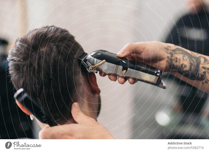 Anonymous young barber cutting hair with machine in hair salon barbershop beard bearded bearded man beauty care client clipping coiffure cutter gentleman guy