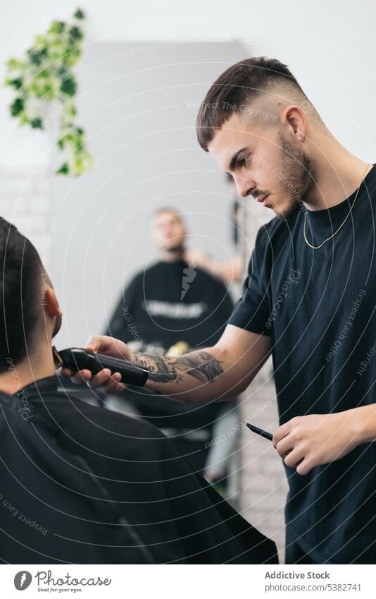 Young barber cutting beard in barber shop barbershop bearded bearded man beauty blade care client clipping coiffure comb cutter guy hair hair salon haircut