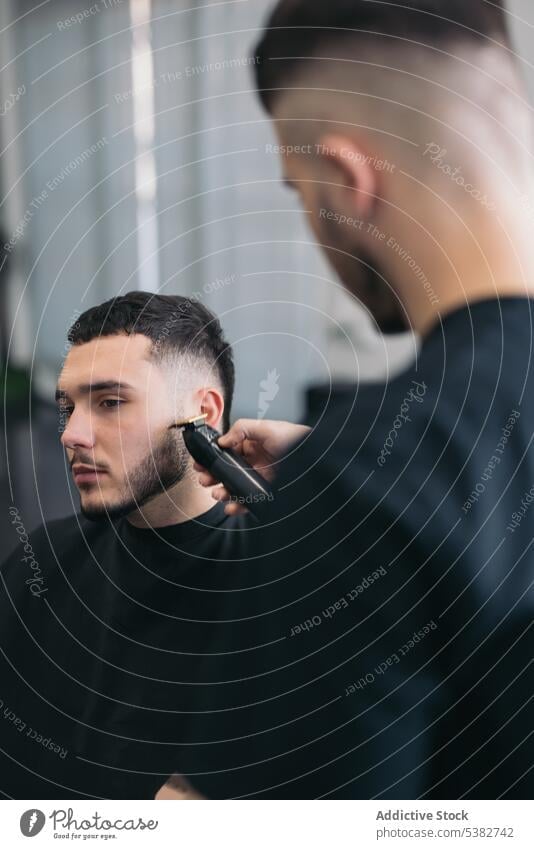 Young barber cutting beard in barber shop barbershop bearded bearded man beauty blade care client clipping coiffure cutter guy hair hair salon haircut