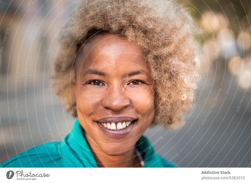 Smiling black woman with curly hair on street portrait positive cheerful happy content smile style city appearance african american ethnic afro female optimist