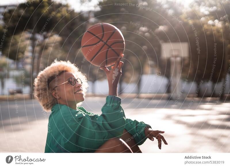 Happy black woman holding basketball up player court sports ground sportswoman park training focus sportswear relax style female african american eyeglasses