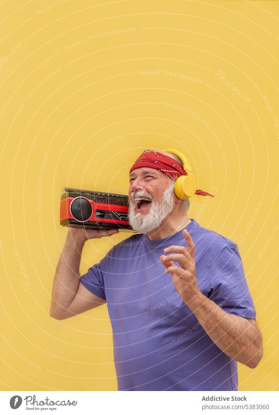 Happy man with cassette player listen to music vintage retro happy headphones aged male positive senior sound smile old cheerful pensioner audio beard studio