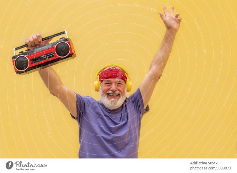 Excited man with cassette player and headphones raising hands happy excited music portrait cheerful retro hands up melody senior elderly male aged old tape
