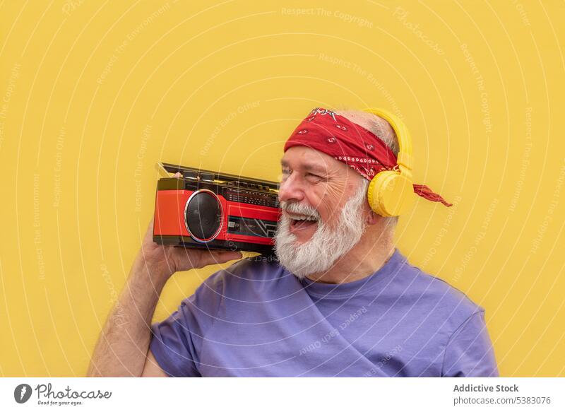Happy senior man with headphones listening to music portrait cassette device gadget sound aged voice beard song audio studio elderly male studio shot loud