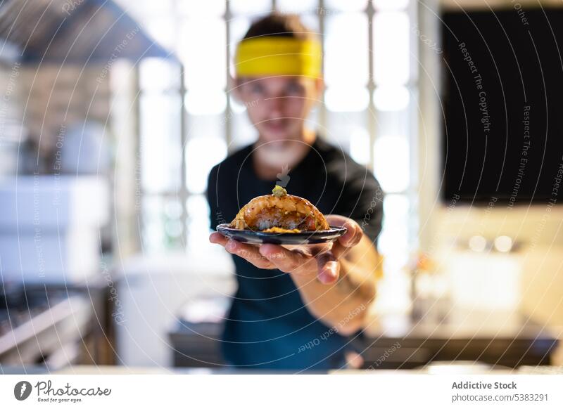 Young man with headband standing and showing nigiri sushi unrecognizable delicious offer food meal tasty seafood appetizing kitchen young male yummy tradition