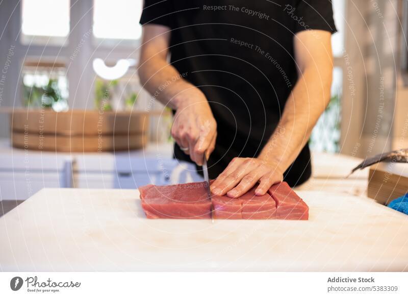 Crop male chef cutting piece of tuna man raw fish kitchen culinary prepare food cook restaurant work table cuisine uncooked ingredient fresh professional modern