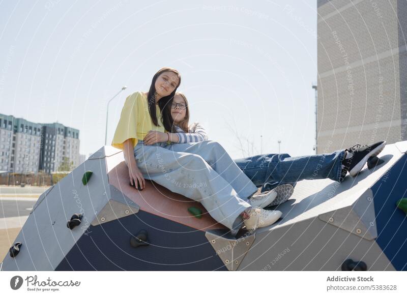 Teen friends spending leisure time in city park girls teenage relax smile together climb wall structure sunny summer teenager young happy carefree casual