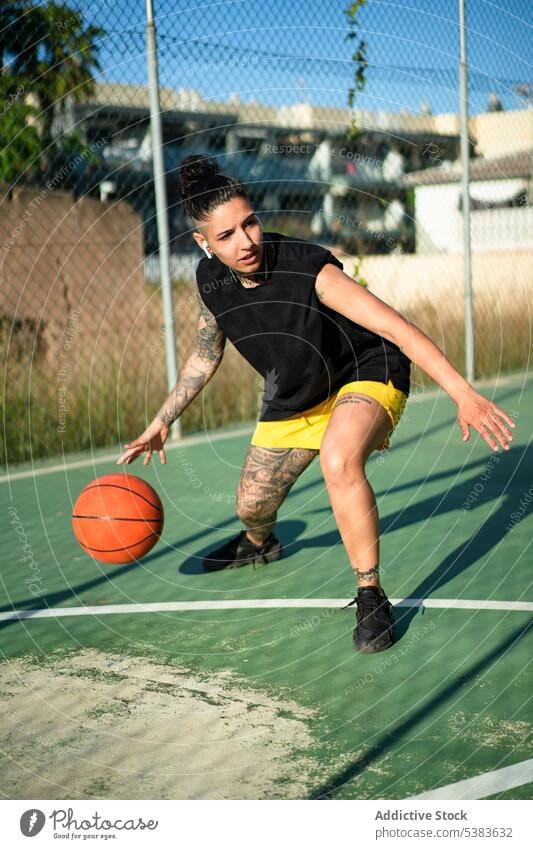 Brutal woman dribbling basketball ball on court sportswoman player dribble sports ground streetball androgynous brutal tattoo masculine playground game female