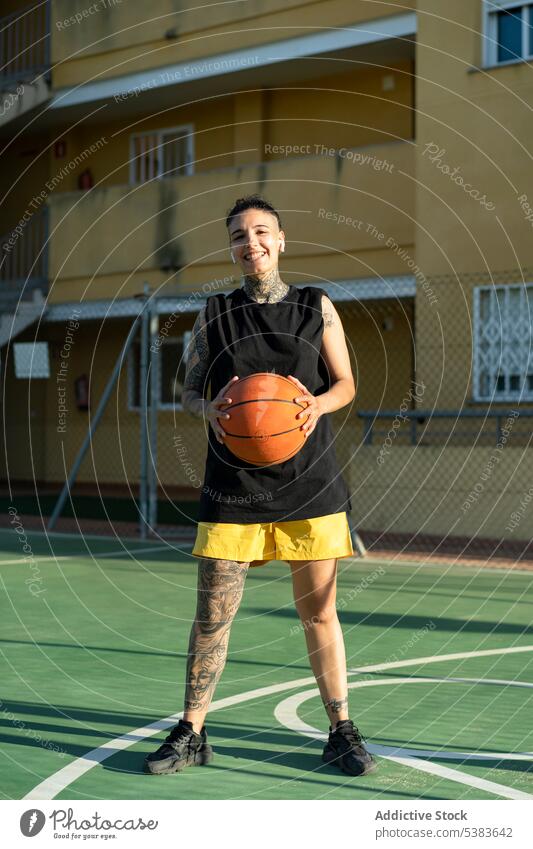 Glad female basketball player with ball on sports ground sportswoman streetball playground game androgynous brutal masculine court training sportswear cheerful