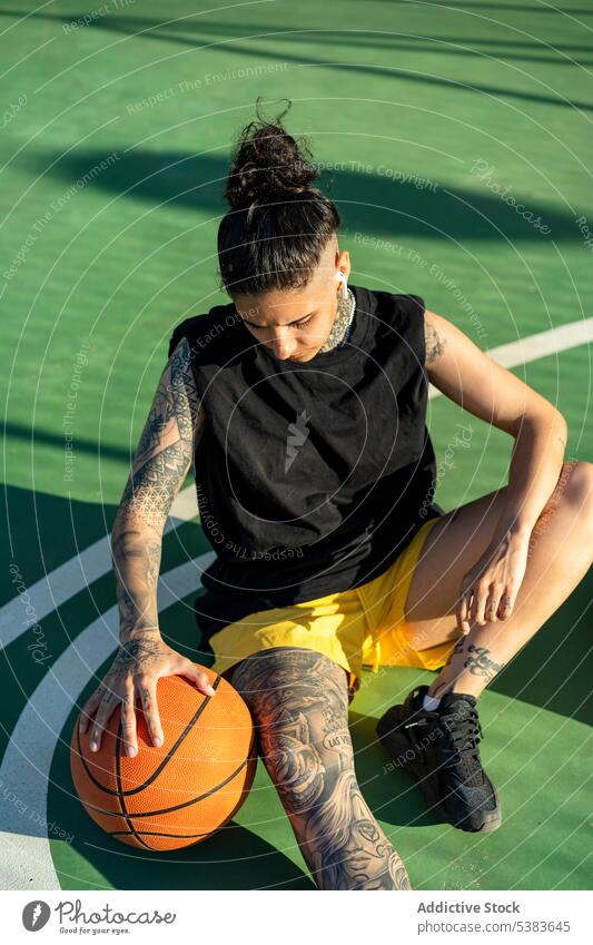 Serious sportswoman with basketball ball resting on playground player sports ground streetball court dreamy brutal androgynous masculine game female training