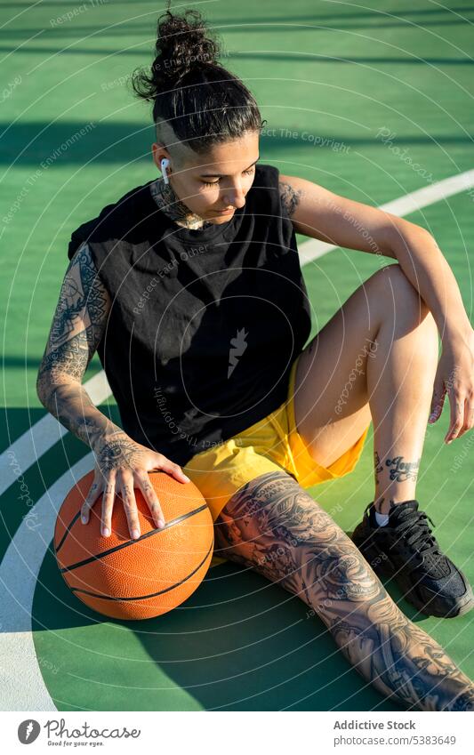 Sportswoman with basketball ball resting on playground sportswoman player sports ground streetball serious court dreamy brutal androgynous masculine game female