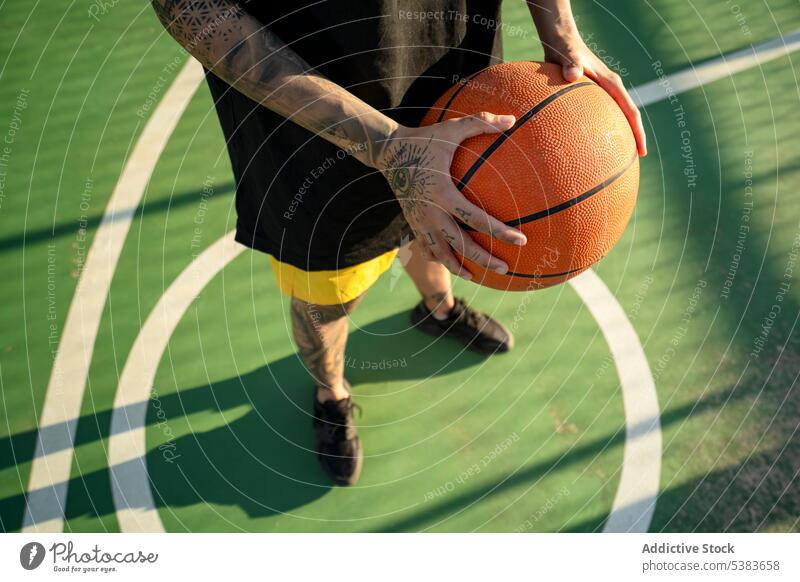 Unrecognizable person with basketball ball on court player sports ground streetball playground game training sportswear sunshine fit sporty hobby style