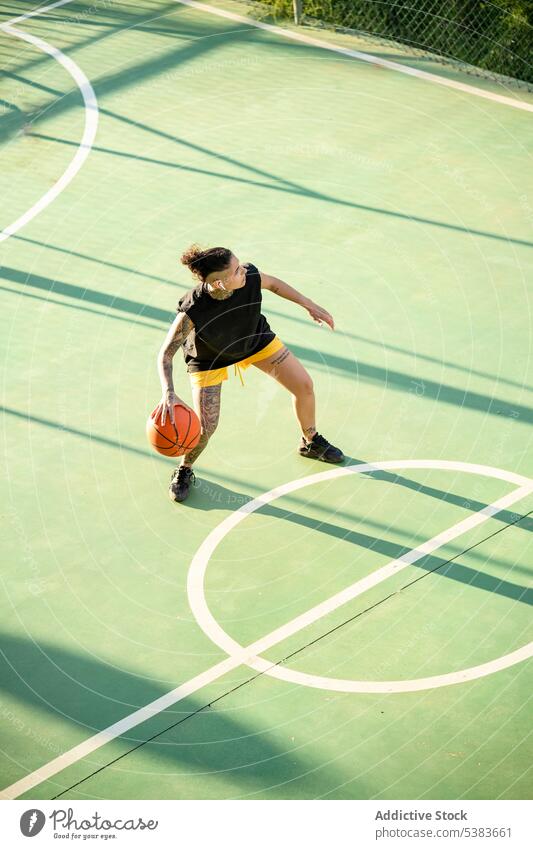 Brutal woman dribbling basketball ball on court sportswoman player dribble sports ground streetball androgynous brutal masculine playground game female training