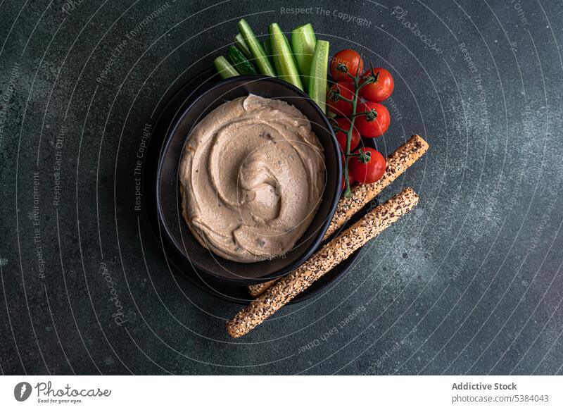 Hummus and vegetables served in a bowl bread stick carrot cherry tomato cuisine dinner dish food healthy hebrew hummus israel lunch oil organic plant based