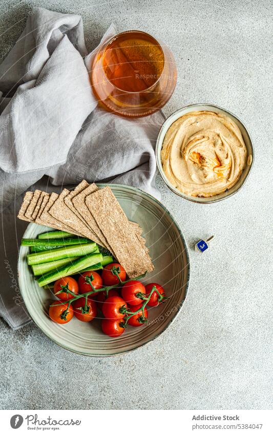 Hummus and vegetables served in a bowl with glass of liquor bread stick cherry tomato cuisine dinner dish food healthy hebrew hummus israel lunch oil organic