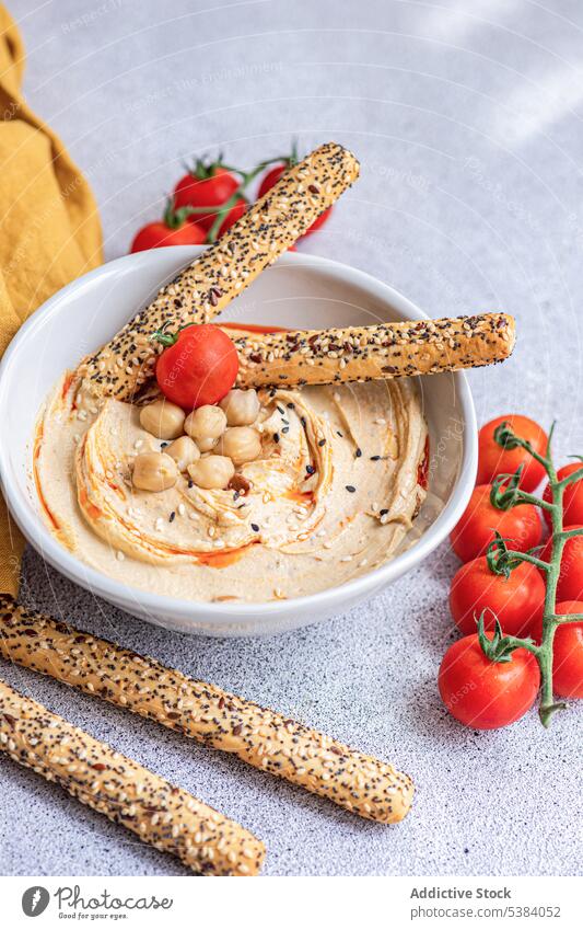 Hummus, tomatoes and bread sticks served in a bowl cherry tomato cuisine dinner dish food healthy hebrew hummus israel lunch oil organic plant based rice bread