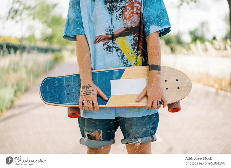 Anonymous shy tomboy with skateboard in park woman anonymous street androgynous skater casual trendy young female pride cool modern optimist satisfied stand