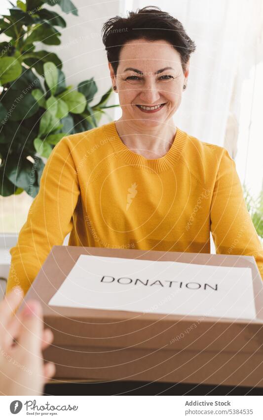 Happy woman with box for donation smile happy donate charity parcel give volunteer apartment positive gift cheerful room work joy home friendly mature glad