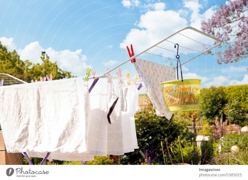 On a sunny day there is a clothes dryer on the terrace for drying white clothes. Collapsible clothes horse with plastic clothespin bag. Plastic basket for clothespins. Space for copying