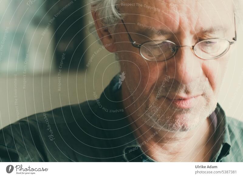 Mainfux | man with glasses looks down thoughtful and absorbed Downward Neutral Background Forehead Earnest Meditative Concentrate Patient Reading Think