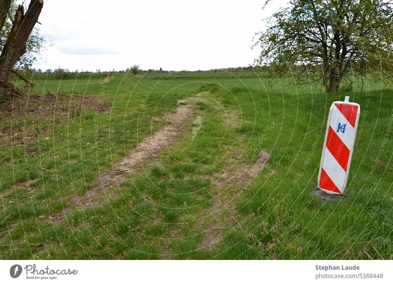 On a dirt road on a former sewage field near Teltow (Potsdam-Mittelmark), a red and white beacon warns of a curve off the beaten track Warn Road sign Caution