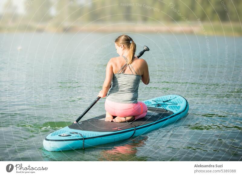 Young athletic woman paddling along the river sitting on the sup board. active activity adventure attractive beach beautiful boarding caucasian exercise female