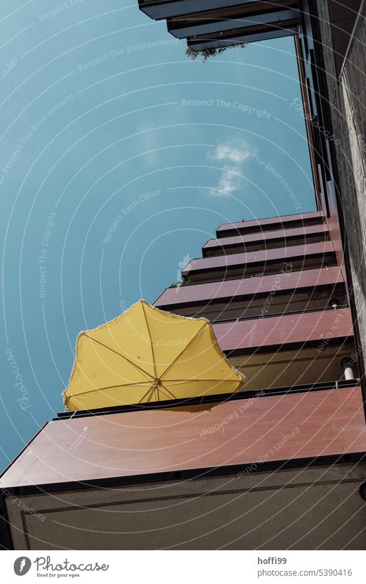 Frog perspective | yellow parasol on a balcony of a skyscraper in front of blue sky - it is hot Sunshade Yellow Balcony glistening light Summer Sky Sunlight
