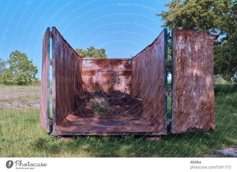 Container with green waste between trees on meadow under blue sky Trash Ecological utilization Sustainability Recycling Environmental protection Dispose of