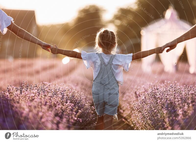 happy family day. young father, mother and child daughter are having fun together in the lavender field and looking at each other. happy couple with kid enjoy summer holiday vacation. family look