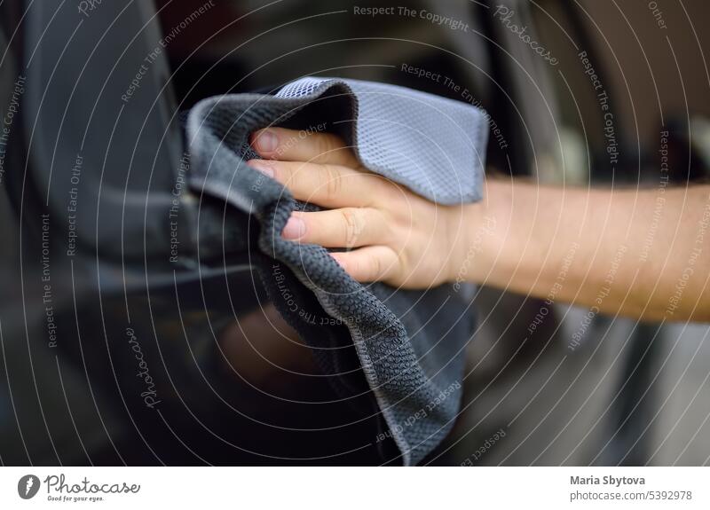 A mature man cleans his car with rag. Driver washes the glass of his car using microfiber washcloth. cleanup manual male care polish auto automobile vehicle