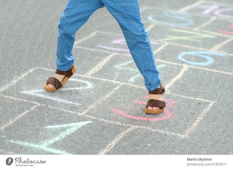 Little boy's legs and hopscotch drawn on asphalt. Child playing hopscotch game on playground on spring day. child chalk jump pavement activity balance childhood