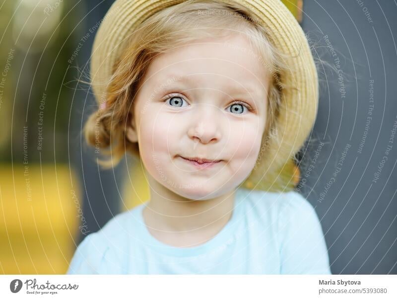 Cute toddler girl outdoors portrait in summer day hat straw compliant caucasian docile kid blonde hair baby eyes blue lady little calm happy curly personality