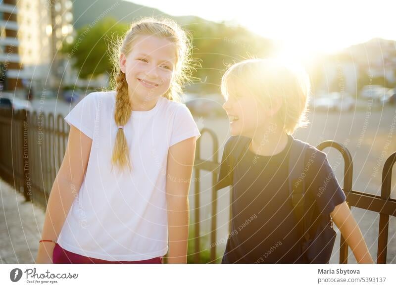 Portrait of a happy preteens girl and boy on a city street during a summer sunset. Friends are walking together. First love kids child portrait friend student